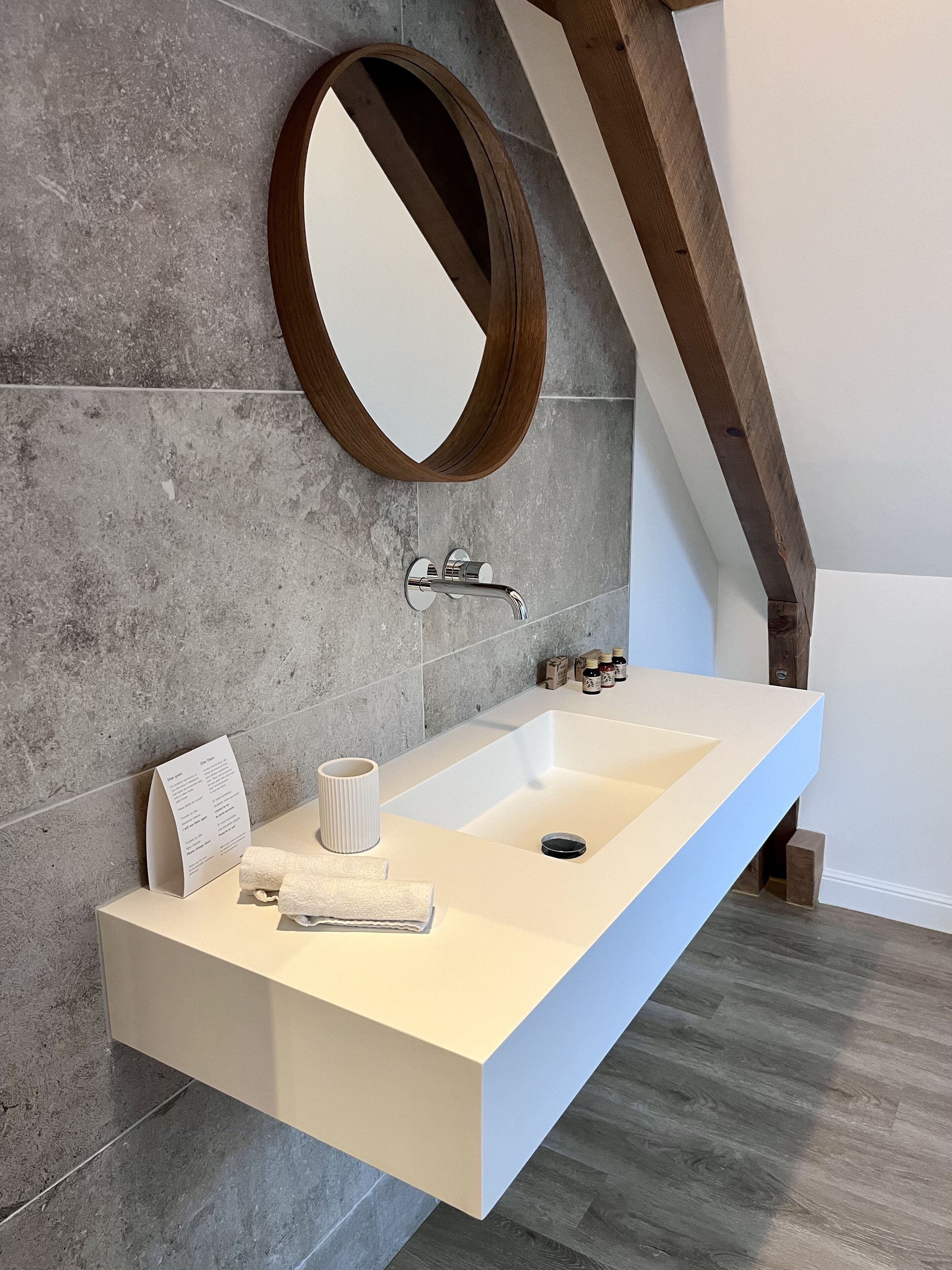 Ein modernes Badezimmer mit einem langen, weißen Waschtisch, einem großen Spiegel und einem integrierten Waschbecken.