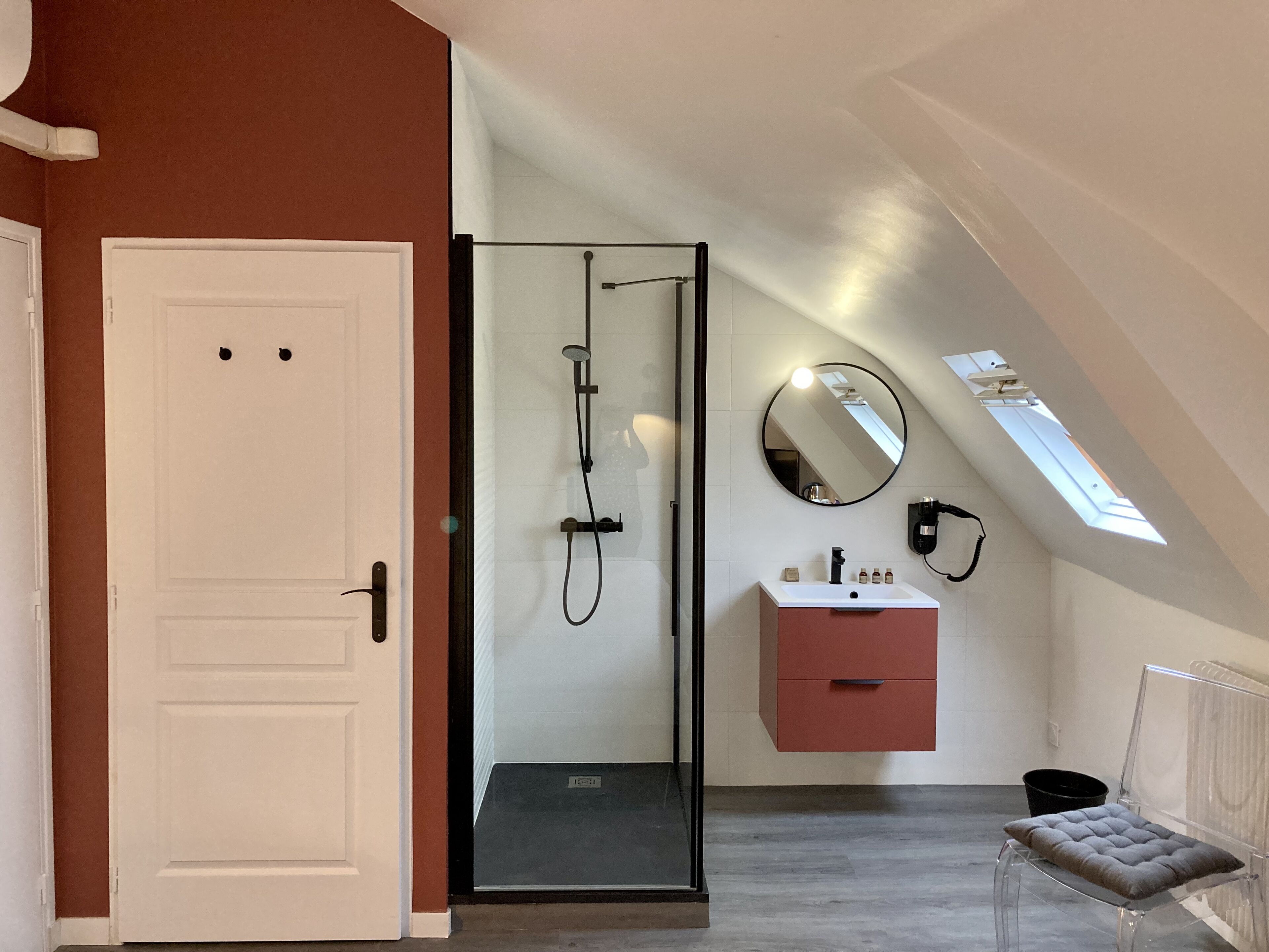 Ein modernes Badezimmer mit Duschabtrennung aus Glas, einem Waschtisch mit Spiegel und einer Sitzbank.