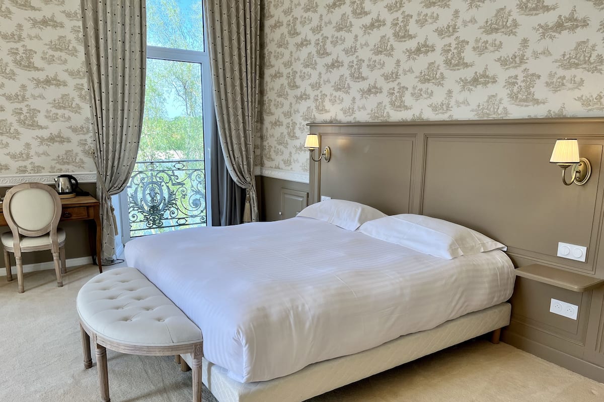 A neatly arranged bedroom with a large bed, a small desk, and a chair.