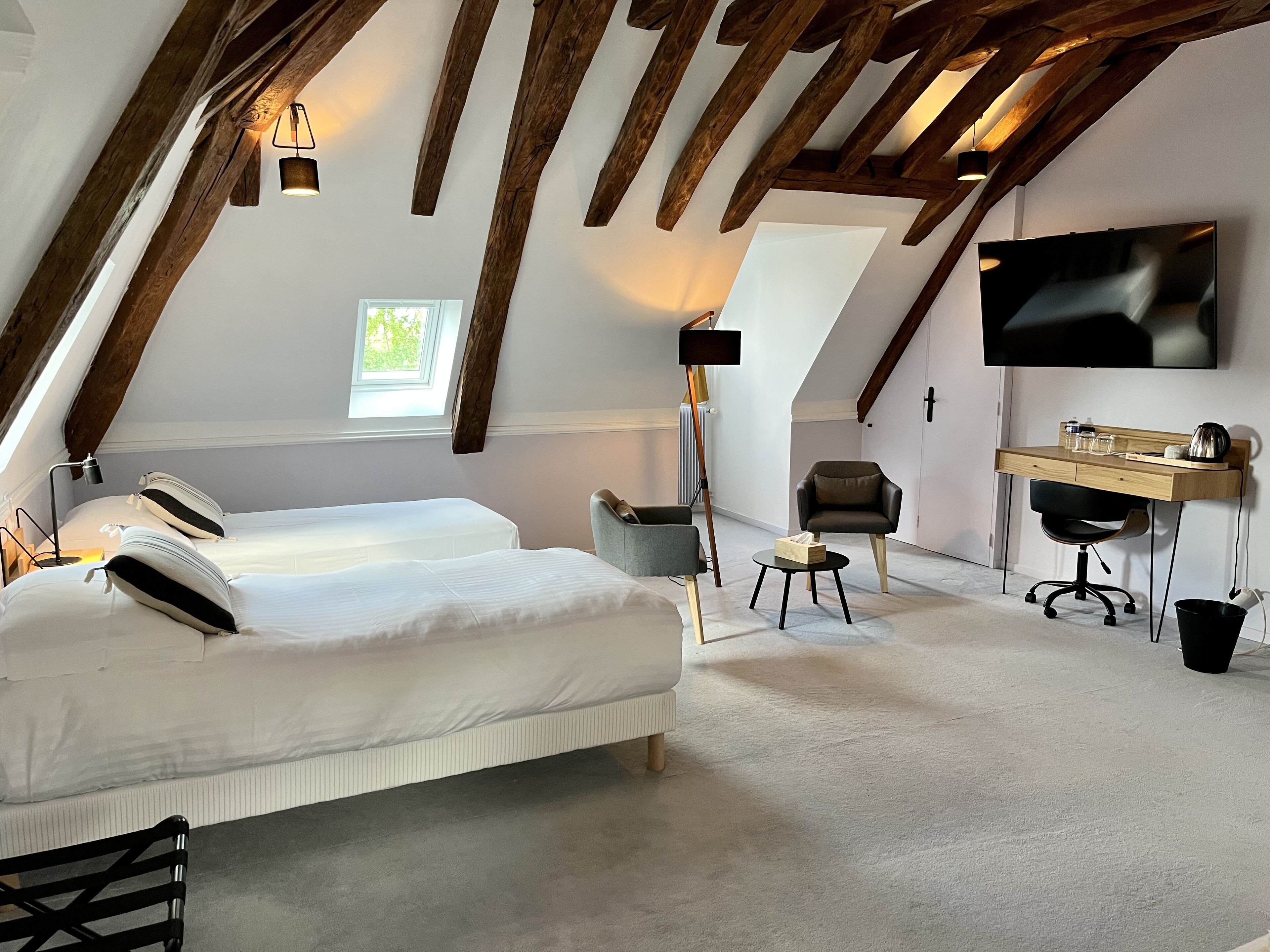 Un dormitorio con una cama grande, un escritorio, una silla y un televisor.