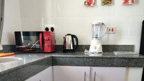 Une cuisine équipée d’un four à micro-ondes, d’un grille-pain, d’une bouilloire et d’un mixeur, le tout posé sur le plan de travail.