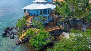A coastal house with a large deck, multiple levels, and a view of the ocean. - Awesome Over The Water Overlooking West End - Aire Agua 3 Bedroom Home by RedAwning (Roatan)