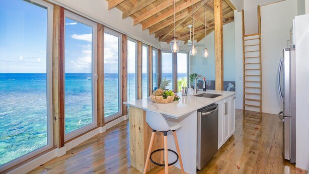 A kitchen with large windows, wooden beams, and a view of the ocean. - Awesome Over The Water Overlooking West End - Aire Agua 3 Bedroom Home by RedAwning (Roatan)