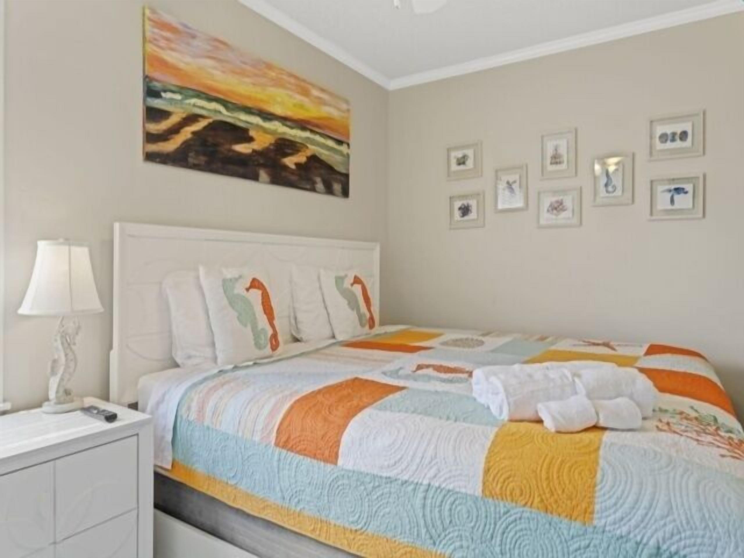 A bedroom with a bed, a nightstand, a lamp, and a painting on the wall.