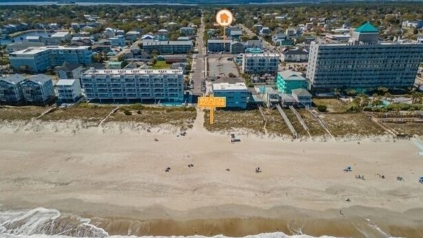 An aerial view of a coastal area with a beach, several buildings, and a prominent yellow sign. - Life's A Beach - Walk To Everything In Historic Carolina Beach! 1 Bedroom Condo by RedAwning (Carolina Beach)