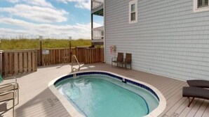 A swimming pool on a wooden deck with a view of the beach and a building with balconies. - Driftwood Cottage - First Floor Oceanfront Beach Retreat! Exceptional Views, Location And Privacy 2 Bedroom Condo by RedAwning (Carolina Beach)