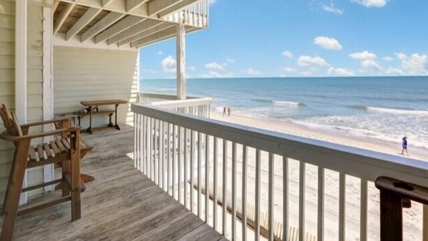 A wooden deck with a view of the beach and ocean.
