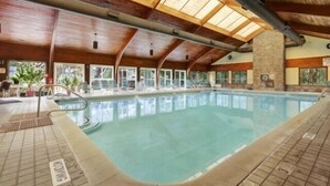 An indoor swimming pool with a wooden ceiling and clear glass windows.