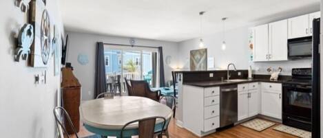 A modern kitchen with a central island, white cabinets, and a dining area with a round table and chairs.