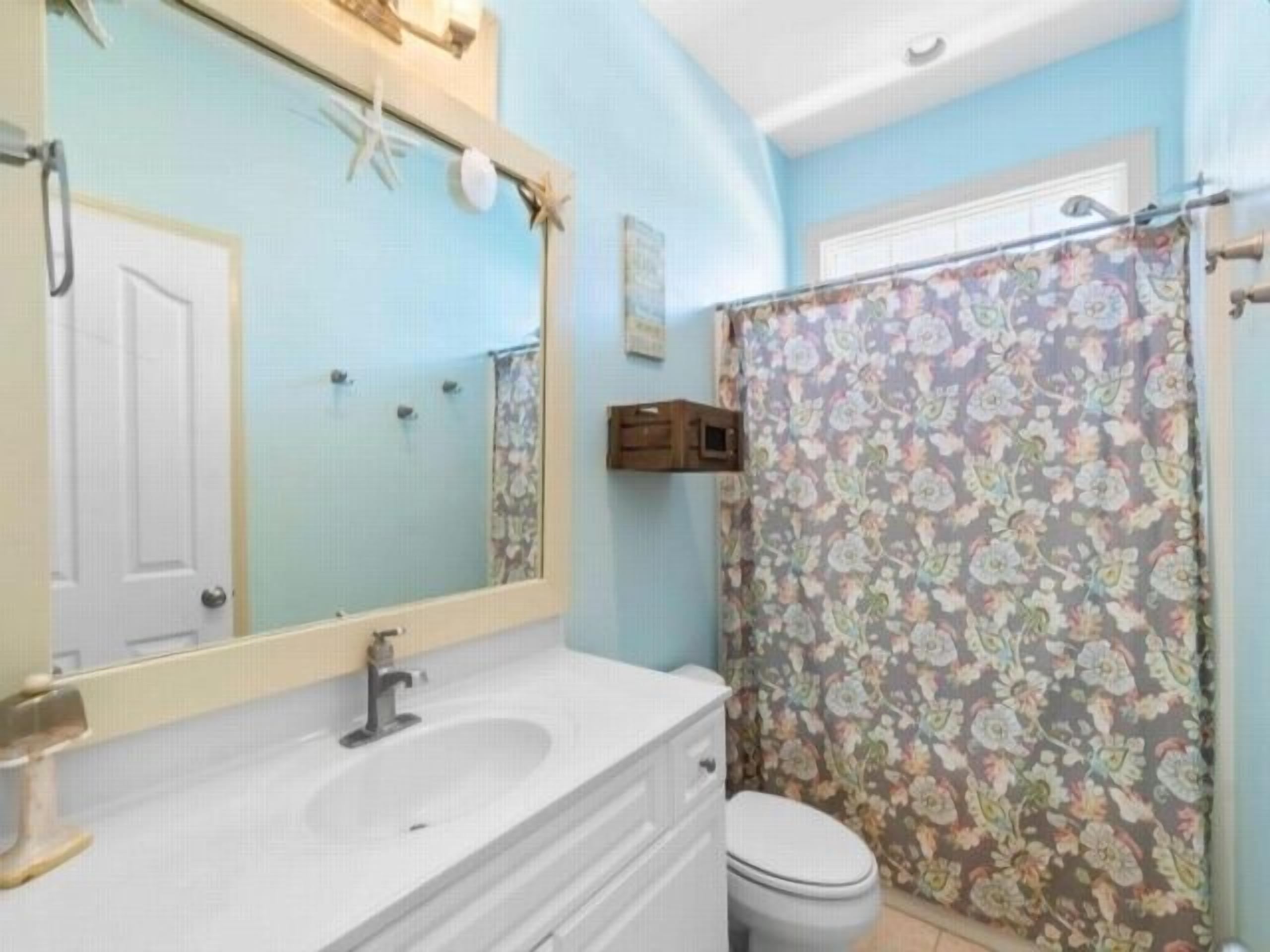A bathroom with a white sink, mirror, and toilet.