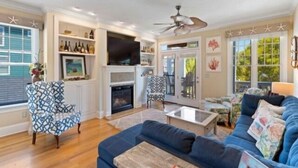 A living room with a fireplace, a television, and a ceiling fan. - After Dune Delight - Relax And Unwind In This Fun And Spacious 3 Story Home. Light, Bright, And Close To Everything! 4 Bedroom Townhouse by RedAwning (Carolina Beach)