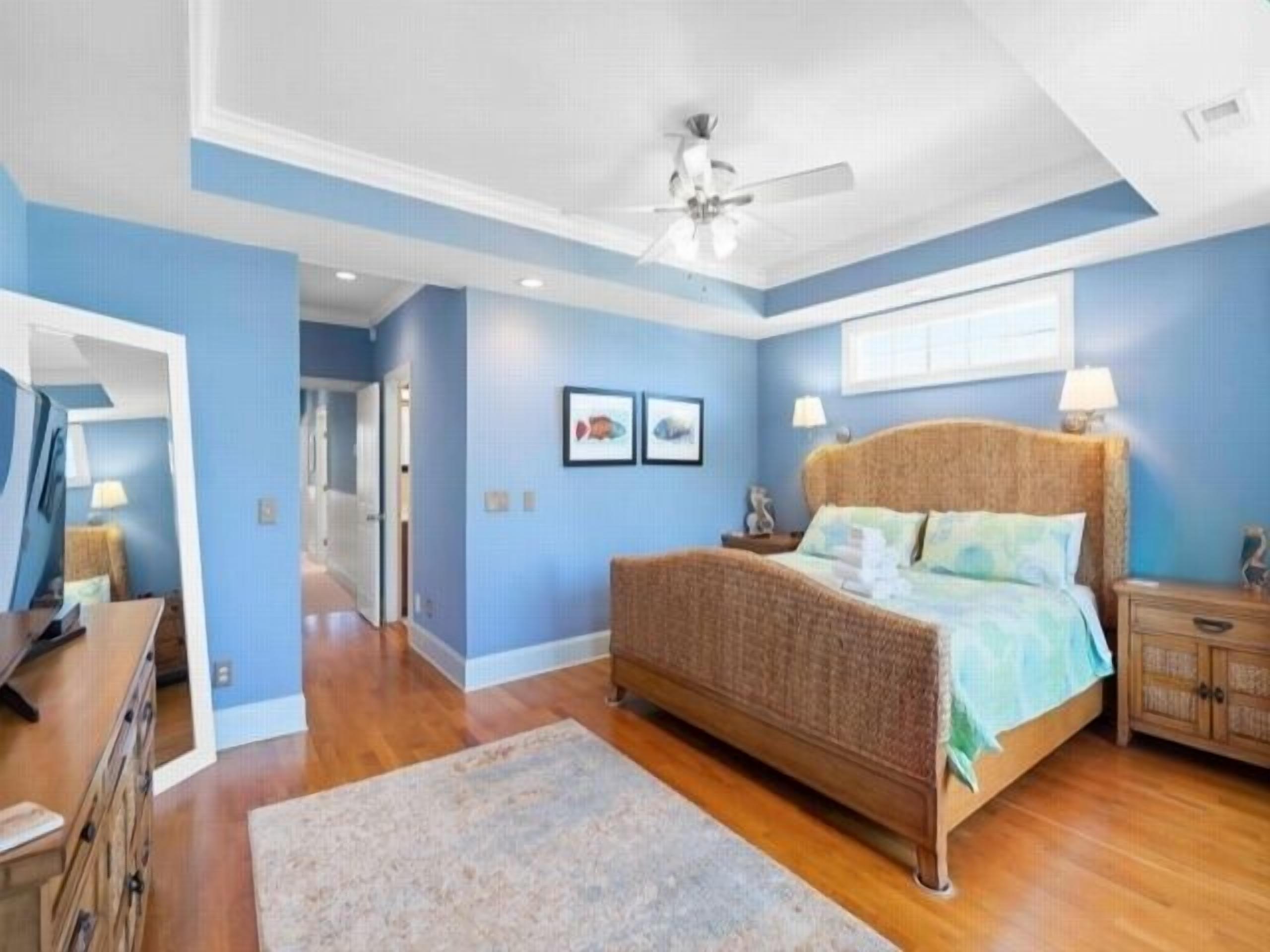A bedroom with a large bed, a ceiling fan, and a wooden dresser.