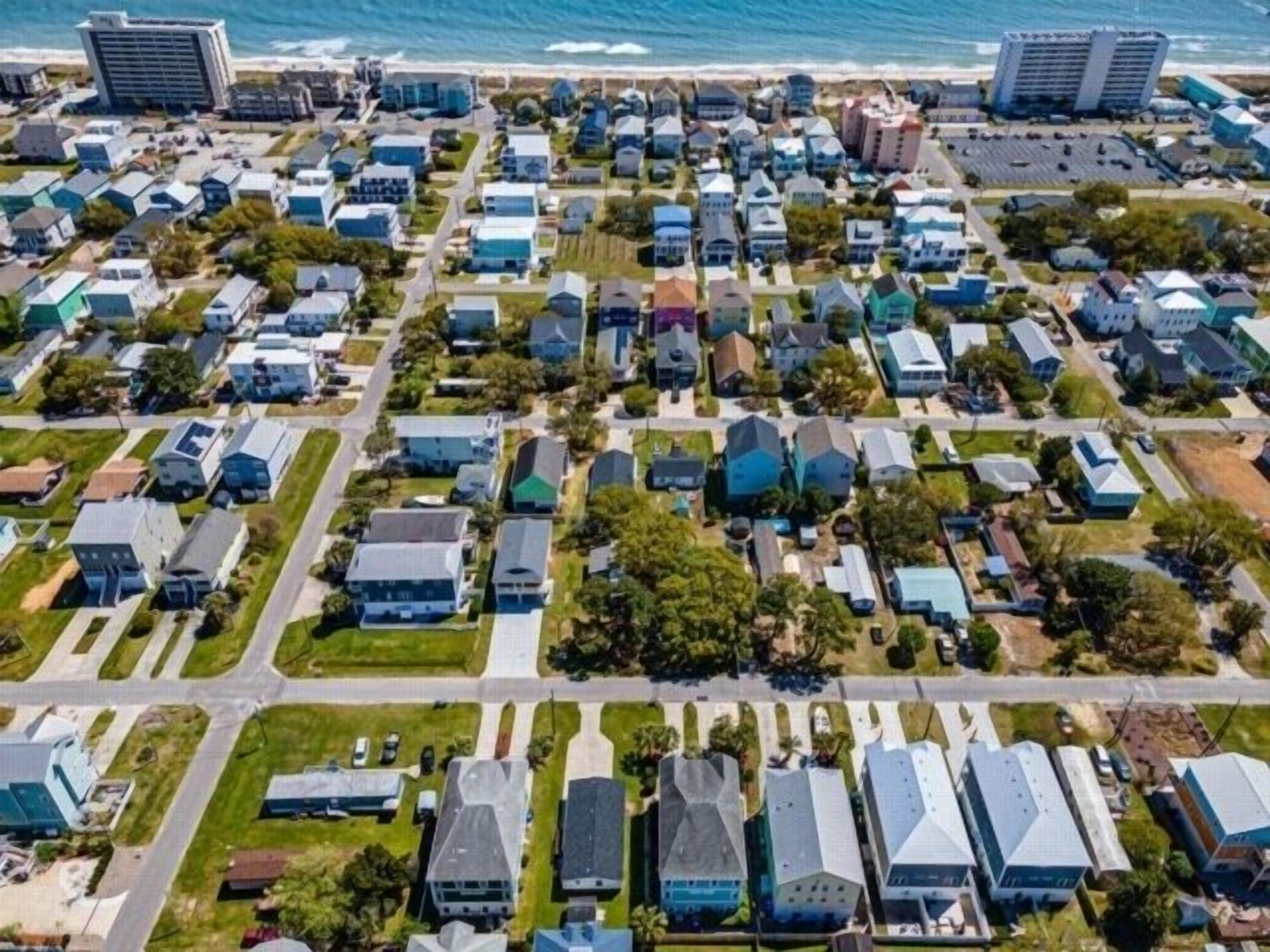 Vista aérea de una zona residencial con casas y una playa al fondo.