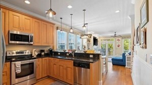 A modern kitchen with wooden cabinets, stainless steel appliances, and pendant lighting. - After Dune Delight - Relax And Unwind In This Fun And Spacious 3 Story Home. Light, Bright, And Close To Everything! 4 Bedroom Townhouse by RedAwning (Carolina Beach)