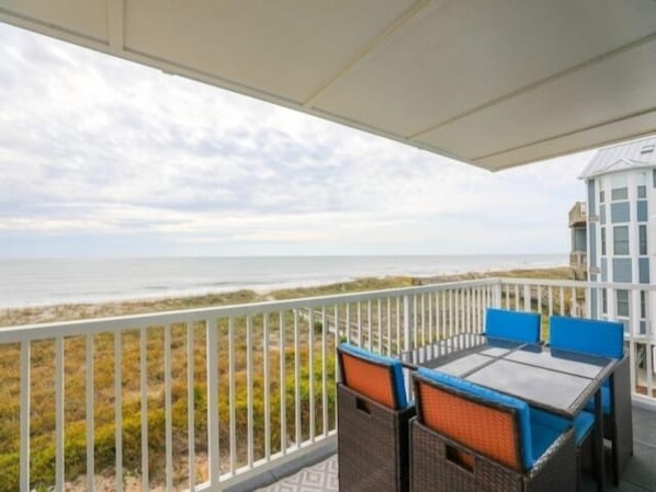 Ein Balkon mit Korbmöbeln und Blick auf den Strand.