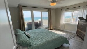 A bedroom with a bed, a ceiling fan, a dresser, and a view of the ocean through large windows. - Carolina Beach Dreamin - Light Filled South Side End Unit. Ocean Views From Most Rooms! Private Beach Access! 3 Bedroom Condo by Redawning (Carolina Beach)