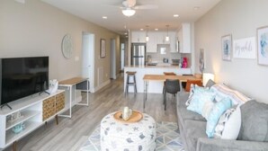 A modern living room with a flat-screen TV, a sofa, and a coffee table. - Carolina Beach Dreamin - Light Filled South Side End Unit. Ocean Views From Most Rooms! Private Beach Access! 3 Bedroom Condo by Redawning (Carolina Beach)
