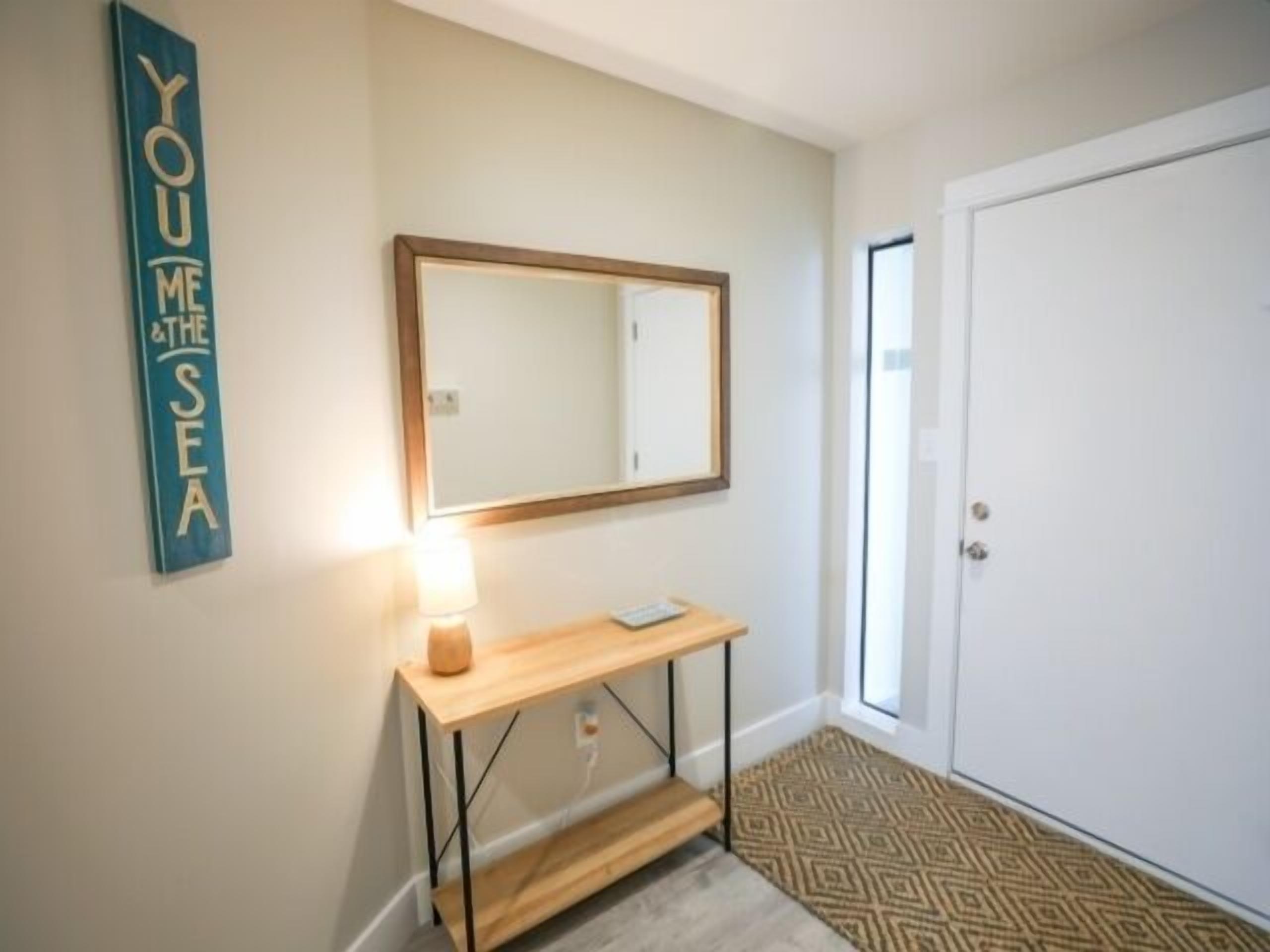 A hallway with a wooden console table, a mirror, and a door.