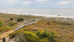 A coastal pathway leading to a beach with a wooden walkway and a trash bin. - Carolina Beach Dreamin - Light Filled South Side End Unit. Ocean Views From Most Rooms! Private Beach Access! 3 Bedroom Condo by Redawning (Carolina Beach)