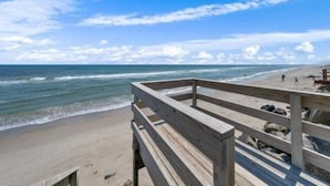 A wooden deck overlooking a beach with waves and a clear sky. - A Shore Thing 2 - Oceanfront And Pet Friendly Home - See The Sunrise, Hear The Waves, Feel The Breeze - Large Oceanfront Balcony 6 Bedroom Townhouse by RedAwning (Carolina Beach)