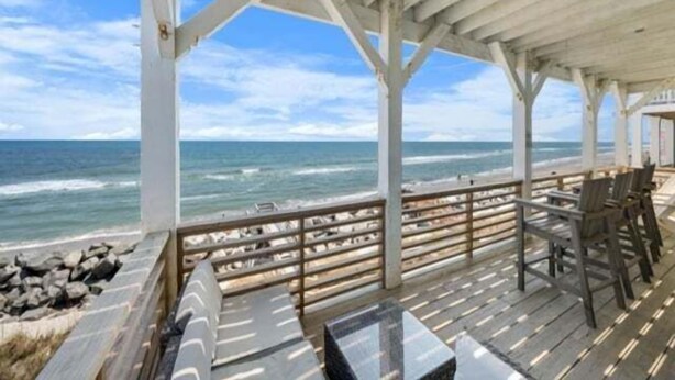 A covered outdoor seating area with a view of the ocean. - A Shore Thing 2 - Oceanfront And Pet Friendly Home - See The Sunrise, Hear The Waves, Feel The Breeze - Large Oceanfront Balcony 6 Bedroom Townhouse by RedAwning (Carolina Beach)