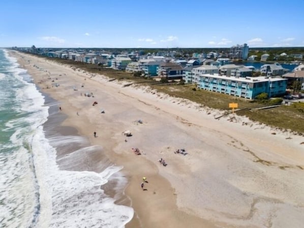 Une plage bordée d’une rangée de bâtiments, comprenant un mélange de logements et, peut-être, d’hôtels.