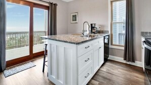 A modern kitchen with a large island, a built-in dishwasher, and a view of the outdoors. - Sea Haven - Oceanfront! Amazing Master Suite With A Private Oceanfront Deck! Recently Renovated And Perfect For The Entire Family 3 Bedroom Home by RedAwning (Kure Beach)