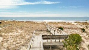 A wooden boardwalk leading to a beach with dunes and a clear sky. - Sea Haven - Oceanfront! Amazing Master Suite With A Private Oceanfront Deck! Recently Renovated And Perfect For The Entire Family 3 Bedroom Home by RedAwning (Kure Beach)