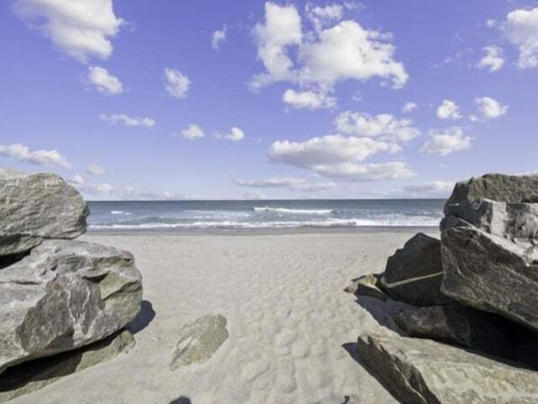 A beach with large rocks in the foreground and the ocean in the background.