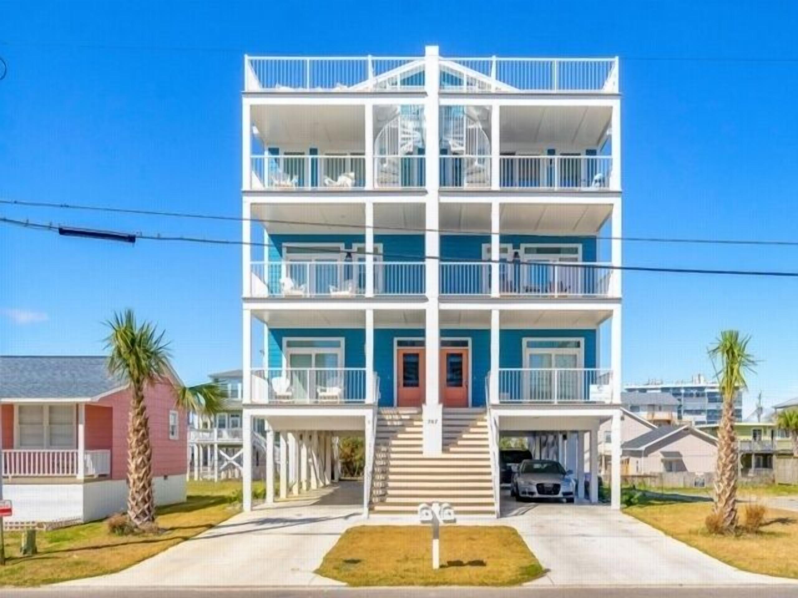 A multi-story residential building with balconies, a front entrance, and a parking area.