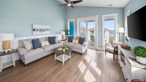 A spacious living room with a ceiling fan, a sofa set, a coffee table, and a TV.