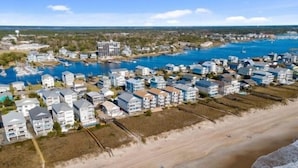 A coastal residential area with beachfront properties, a marina, and a clear view of the ocean.