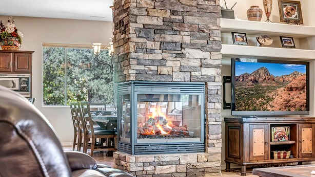 A living room with a stone fireplace, a television, and a leather couch.