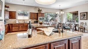 A spacious kitchen with granite countertops, wooden cabinets, and a large island.
