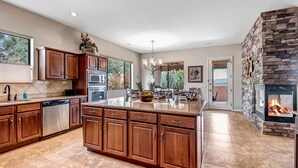 A spacious kitchen with wooden cabinets, a large island, and a stone fireplace.