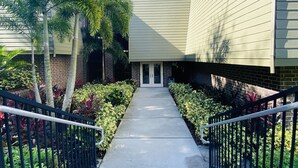 A pathway leading to a building with a brick facade and a flat roof. - Peaceful condo nestled in the heart of Innisbrook (Palm Harbor)