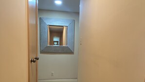 A hallway with a striped floor, a door on the left, and a wall-mounted mirror. - Peaceful condo nestled in the heart of Innisbrook (Palm Harbor)