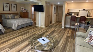 A compact living space with a bed, a glass coffee table, a kitchenette, and a TV mounted on the wall. - Peaceful condo nestled in the heart of Innisbrook (Palm Harbor)
