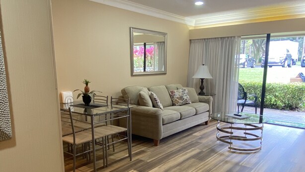 A modern living room with a sofa, dining table, and chairs. - Peaceful condo nestled in the heart of Innisbrook (Palm Harbor)