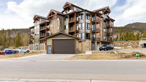 A multi-story building with a garage, balconies, and a mountainous backdrop. - 204 Clearwater Lofts 2 Bedroom Condo by RedAwning (Keystone)