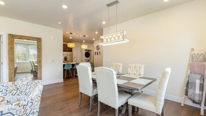 A dining area with a wooden table, six upholstered chairs, and pendant lighting. - 204 Clearwater Lofts 2 Bedroom Condo by RedAwning (Keystone)