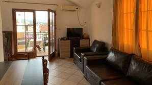 Ein Wohnzimmer mit einer Couch, einem Fernseher und einem Esstisch.