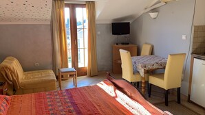 Ein Schlafzimmer mit Bett, Schreibtisch, Stuhl, Fernseher und Kühlschrank.