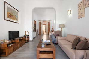 A spacious living room with a television, wooden furniture, a beige sofa, and a coffee table.