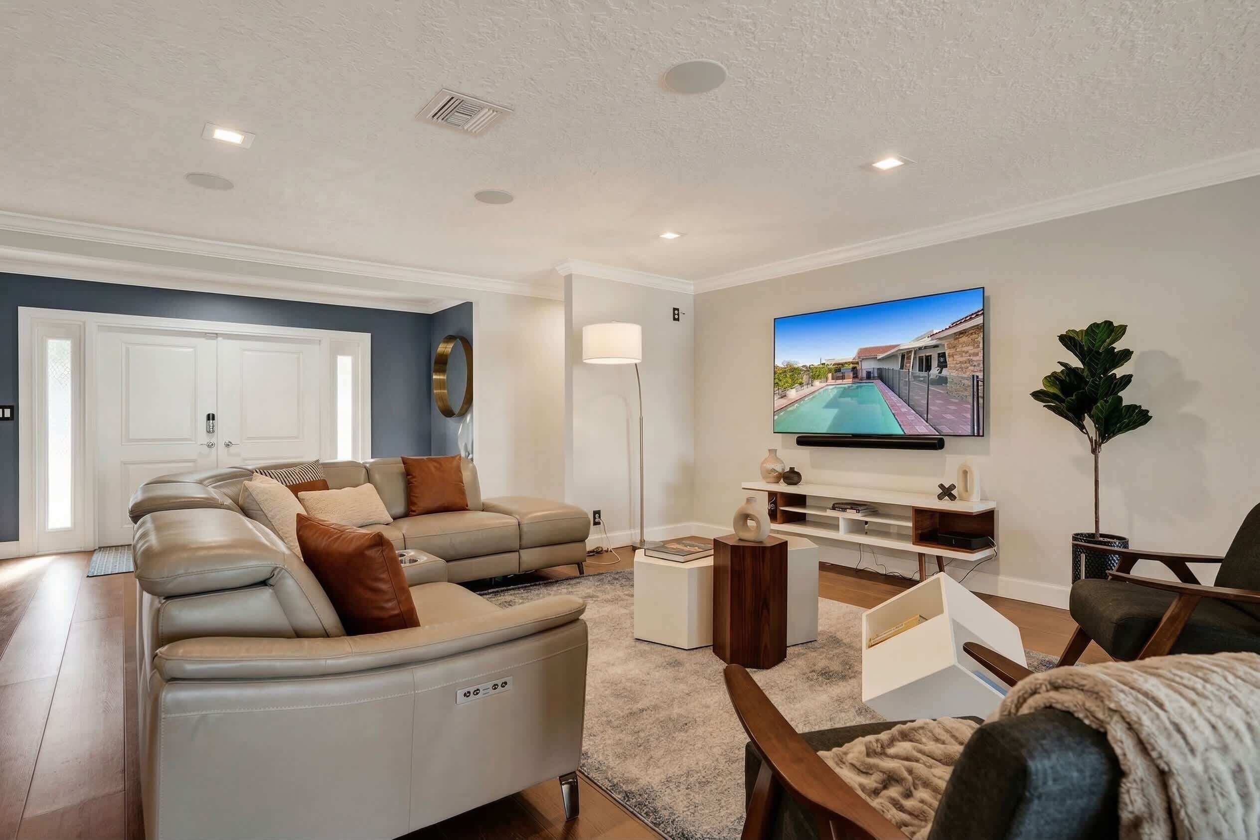 A modern living room with a sectional sofa, a flat-screen TV, and a large window.