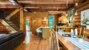 Ein Holzblockhaus-Interieur mit Essbereich, Küche und Treppe.
