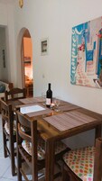 Un comedor con una mesa de madera, sillas y una botella de vino.