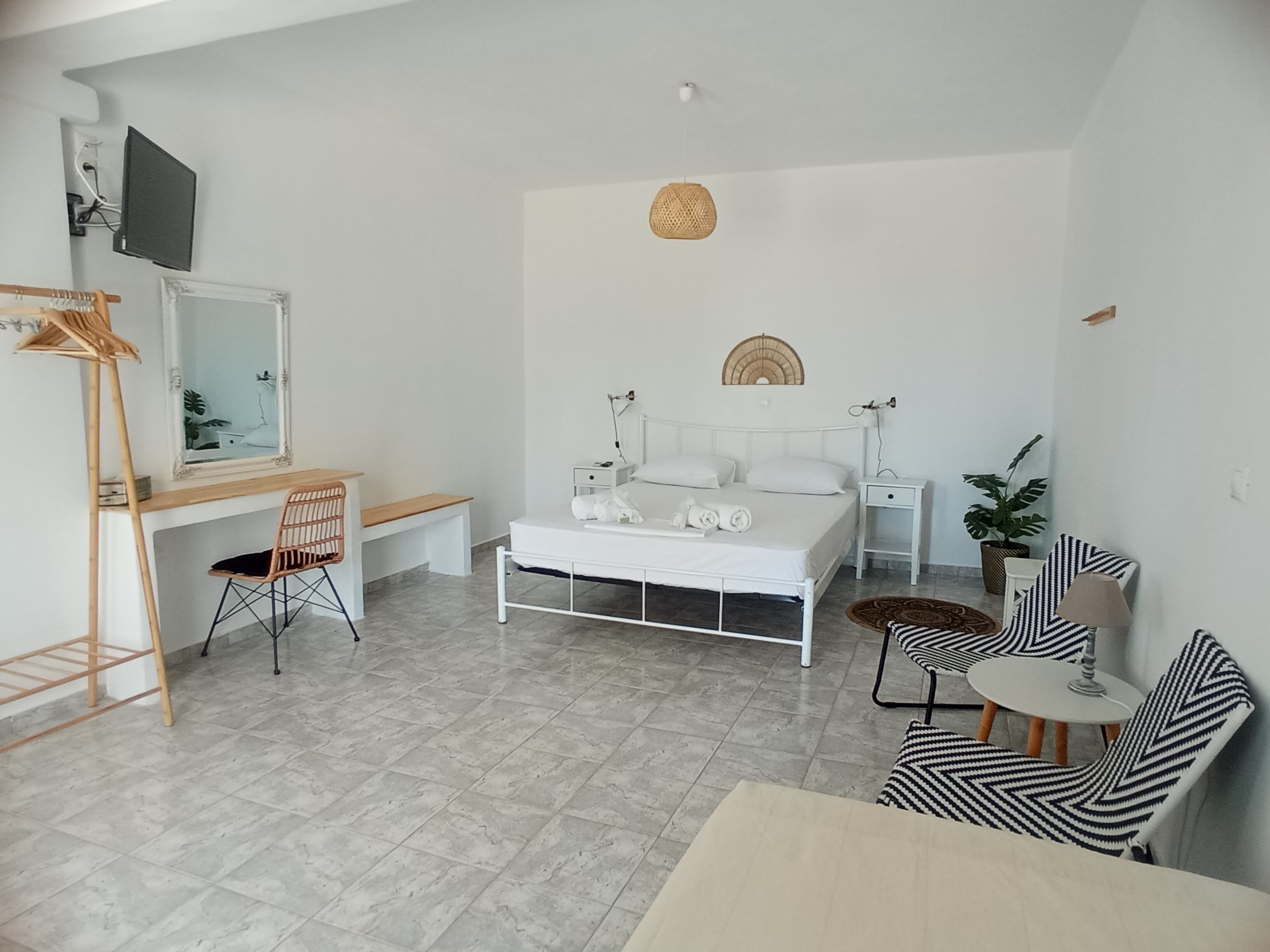 Et moderne, minimalistisk soveværelse med seng, sengeborde, skrivebord og stol.