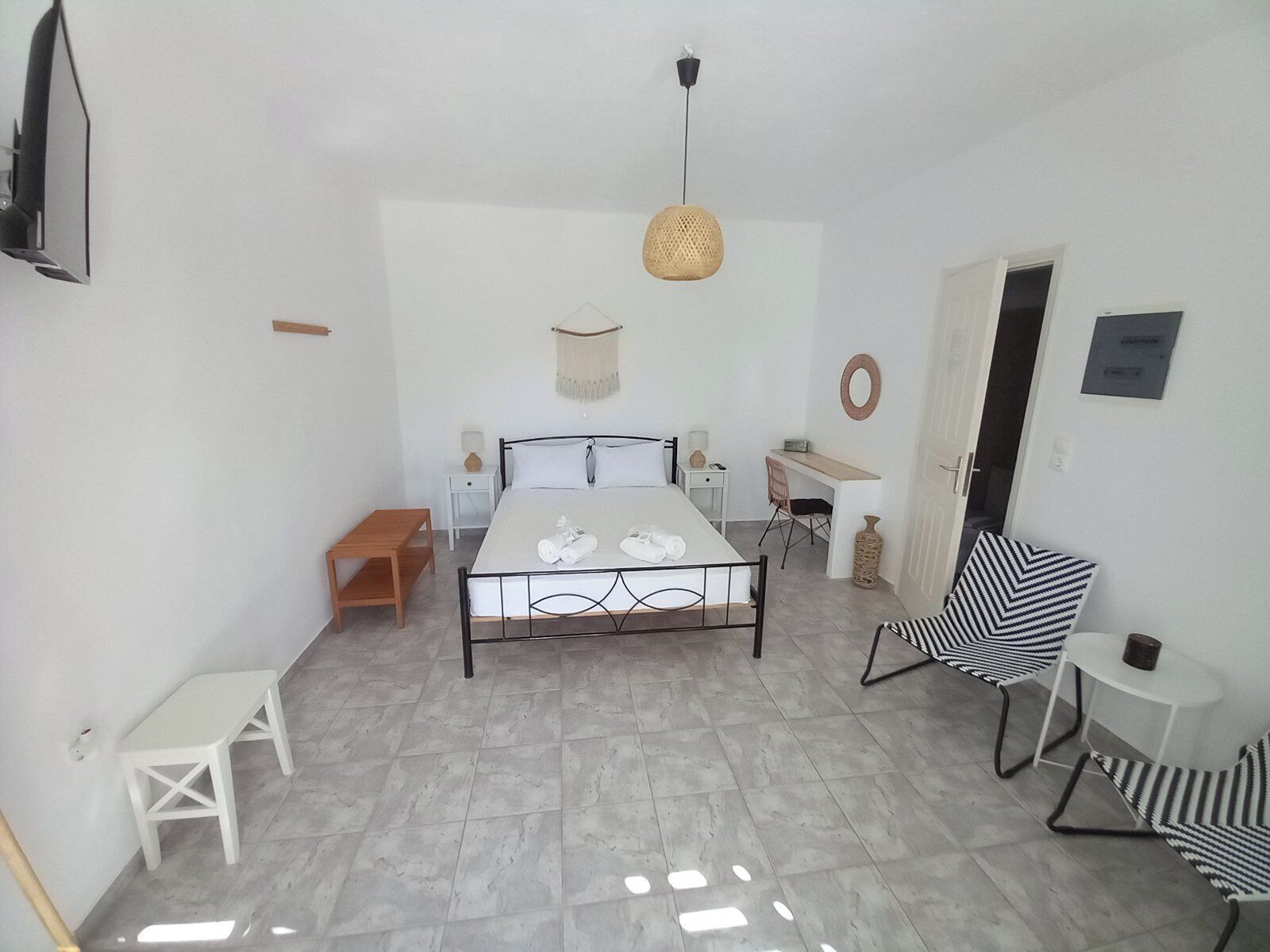 A bedroom with a bed, bedside table, lamp, chair, and a small table.