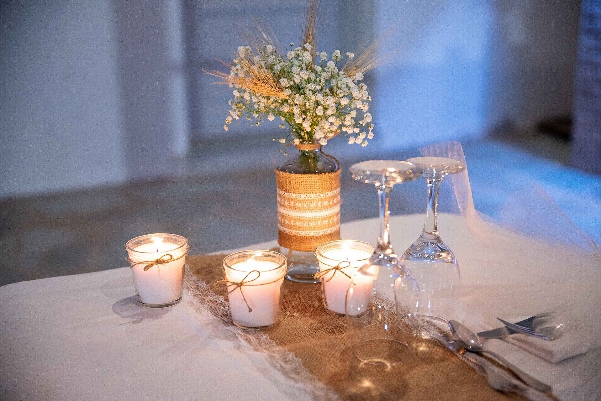 A table set with candles, a vase with flowers, and cutlery.